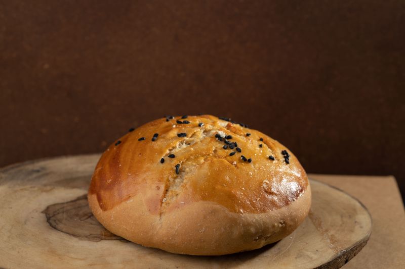 Single sesame brioche bun close-up with seeds.
