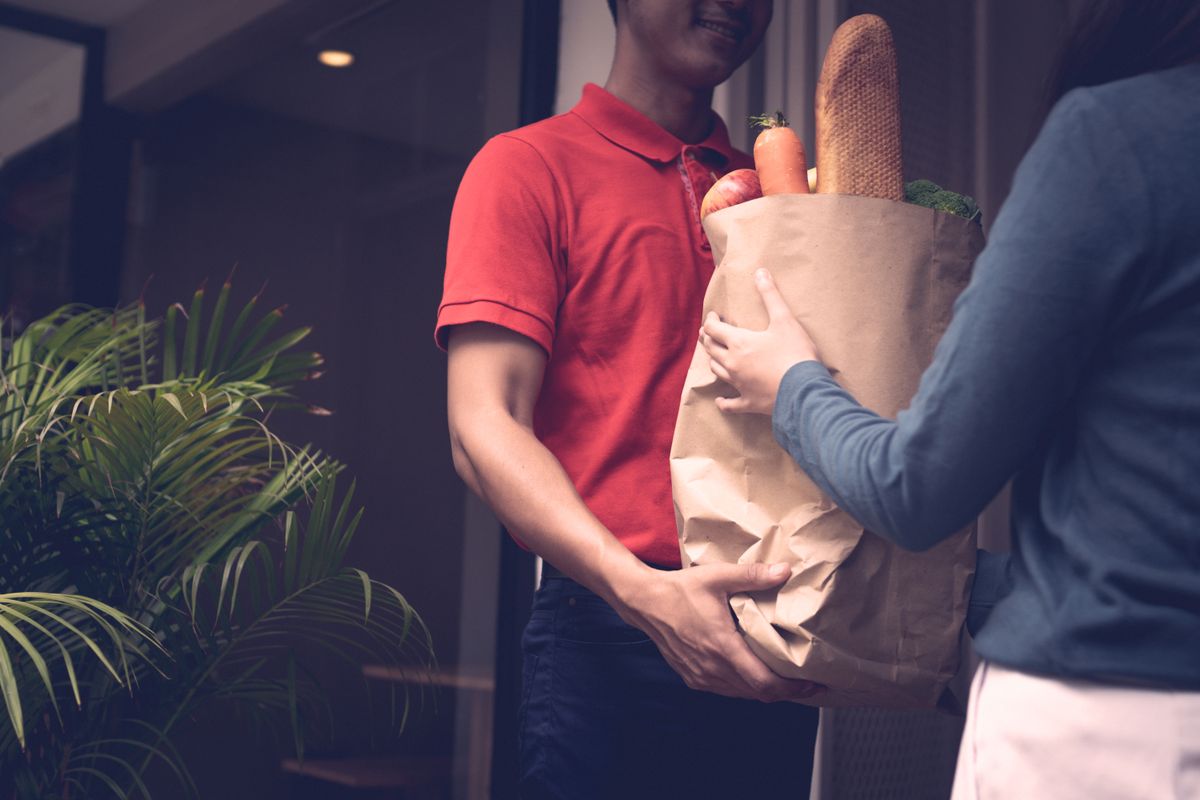 A baker handing off a paper bag of fresh bread at dawn.